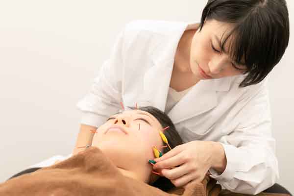 顔に刺さった鍼に電気を流す様子